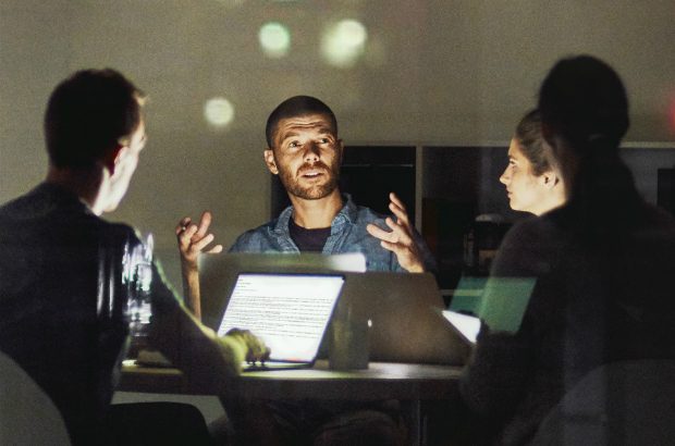 A business meeting at night illuminated by a laptop