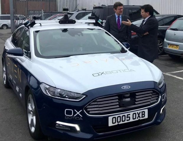 Greg Clark standing beside an Oxbotica car.