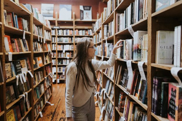 Woman holding book on bookshelves