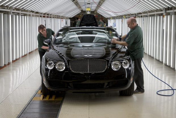 2 workers adding finishing touches to a Bentley car.