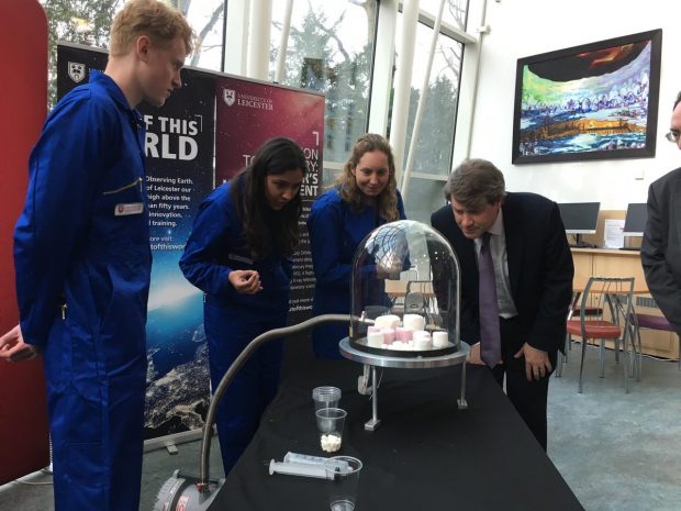 Chris Skidmore with students looking at marshmallows in a vacuum chamber.