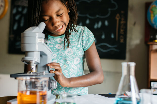 Girl in a classroom looking through a microscope