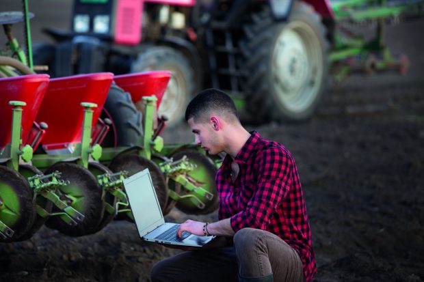 Farmer in a field with a laptop