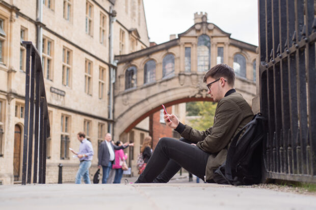 Man looking at phone with the Bridge of Sighs in the background